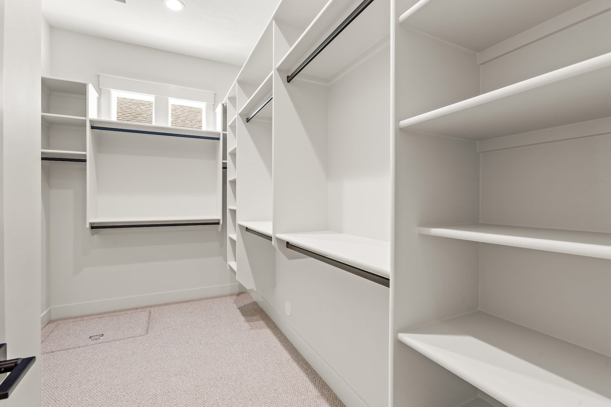 White walk-in closet with shelves and a window