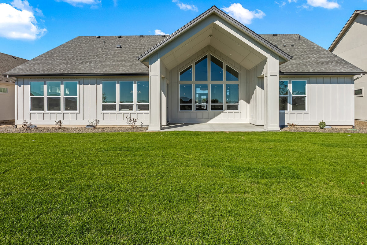 Modern house with large windows and a green lawn on a clear day