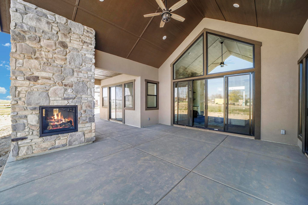 Outdoor patio area with stone fireplace and large glass windows