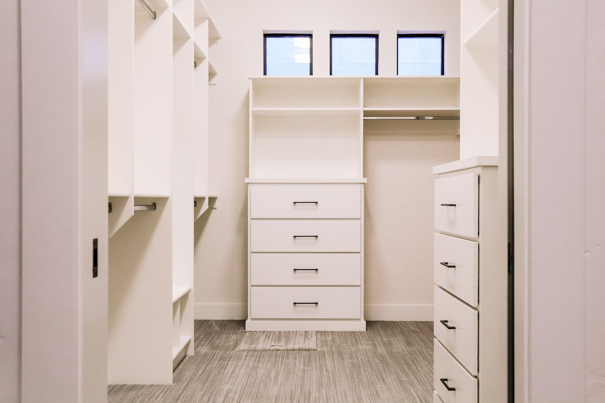 Modern walk-in closet with white drawers and shelves.