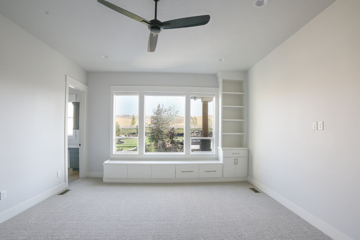 Empty room with large windows, white walls, and a ceiling fan.