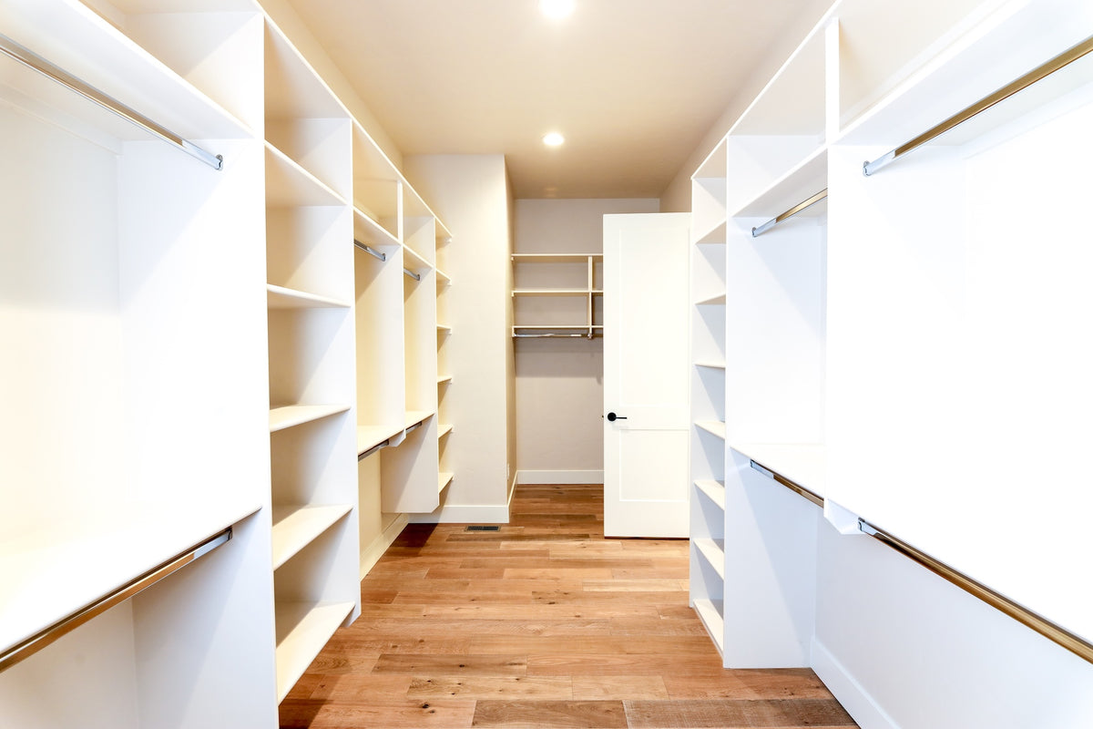 Modern walk-in closet with white shelves and wooden floor