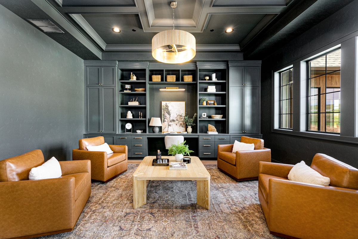 Modern living room with brown leather sofas, a coffee table, and decorative shelves.