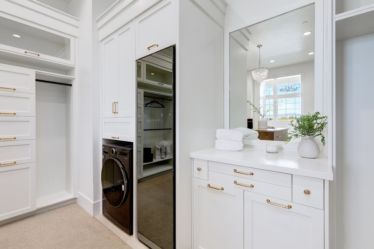 Modern bathroom with white cabinets, washer dryer, and vanity area.