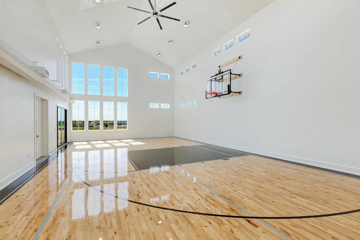 Indoor basketball court with wooden floor and large windows