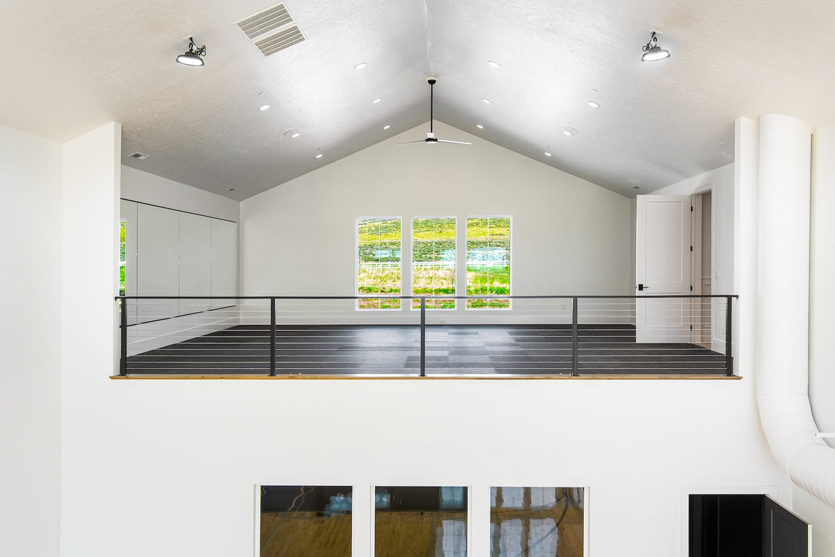 Modern indoor riding arena with white walls and a glass wall window.