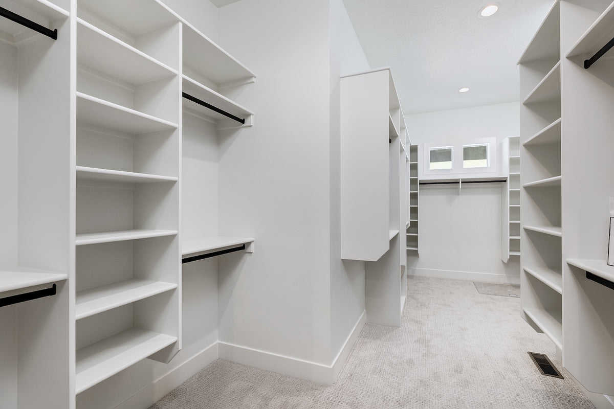 Modern walk-in closet with white shelves and a mirror.