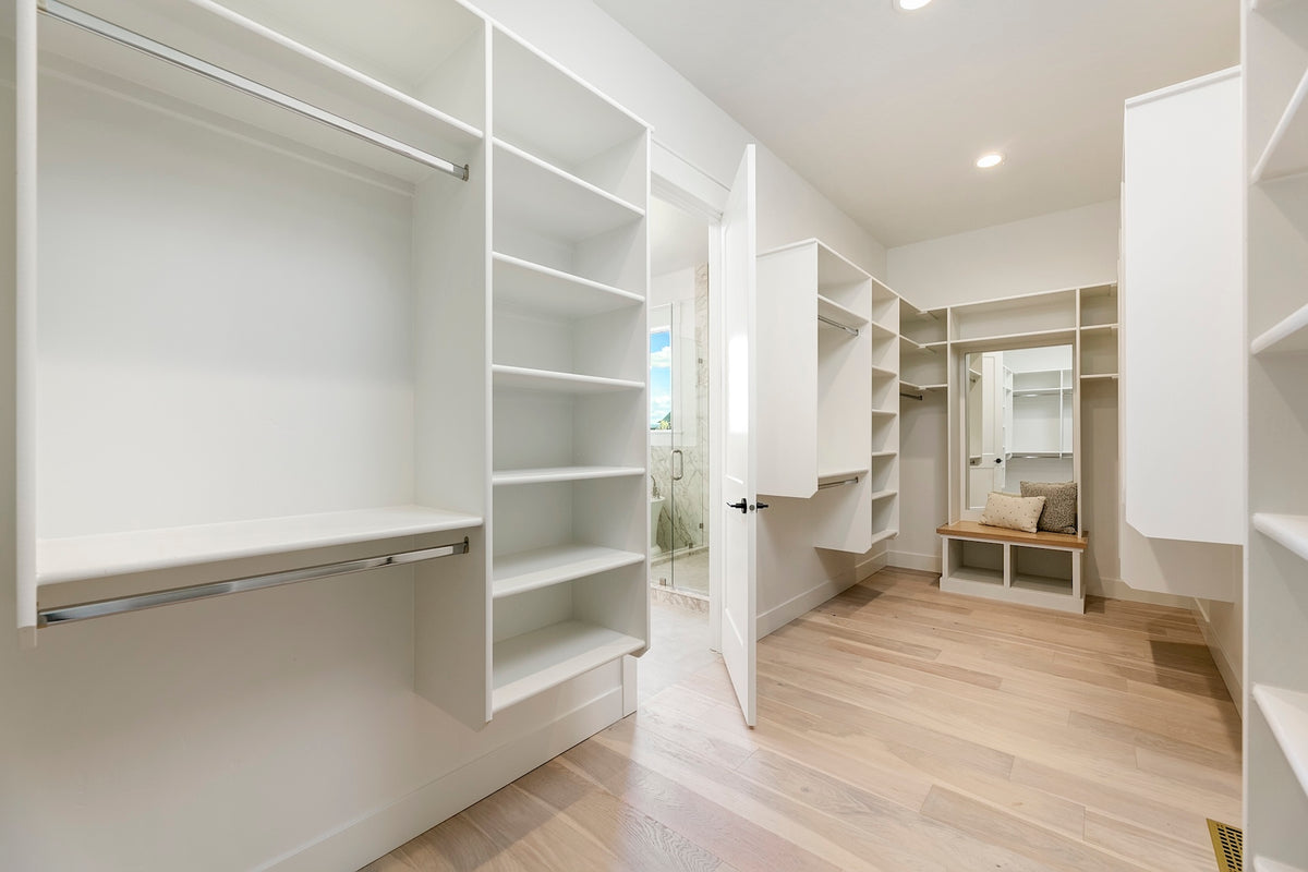 Modern walk-in closet with white shelves and wooden flooring