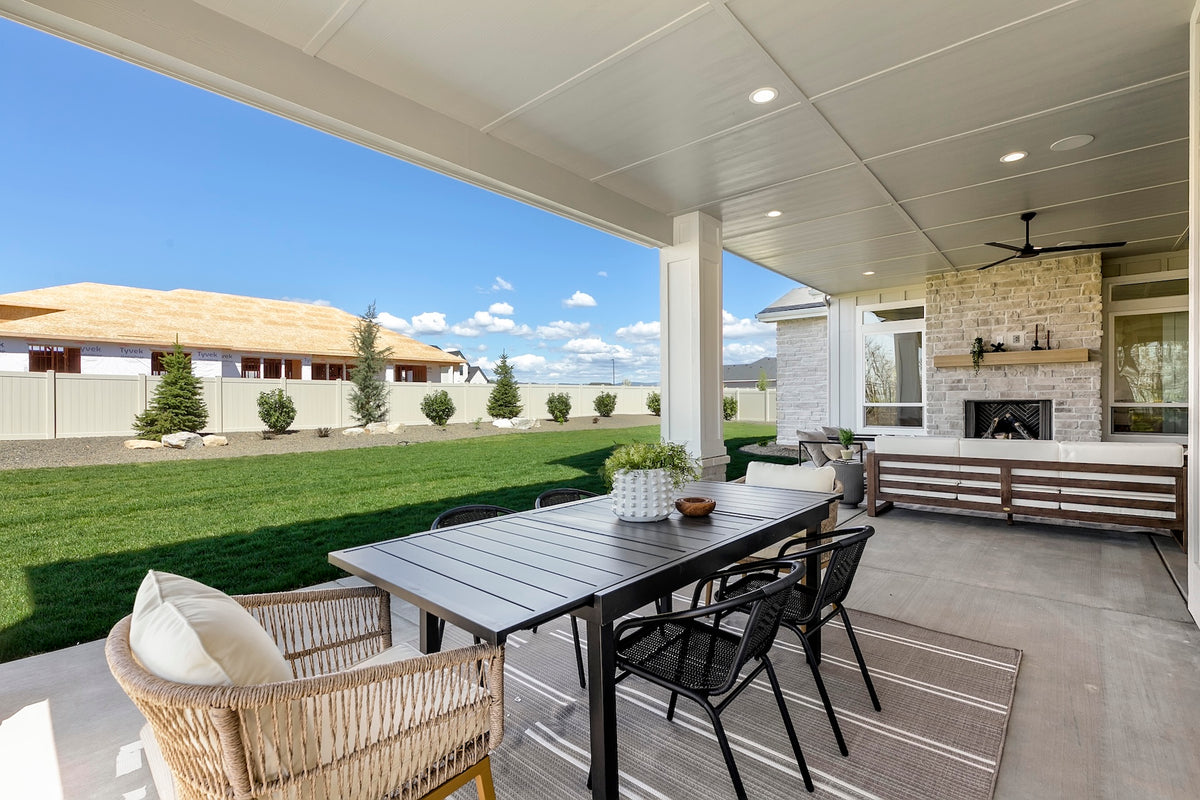 Outdoor patio area with a table and chairs under a covered deck.