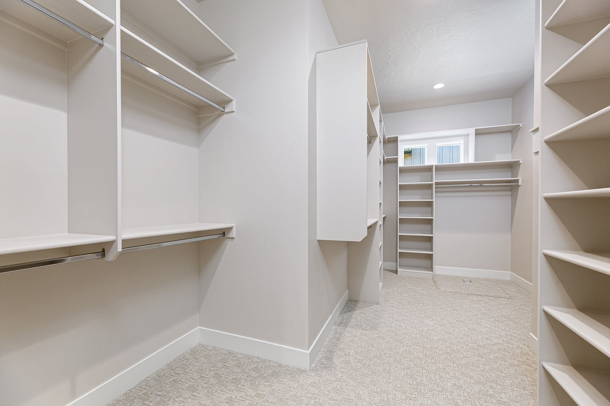 Empty walk-in closet with white shelves and a neutral color scheme.