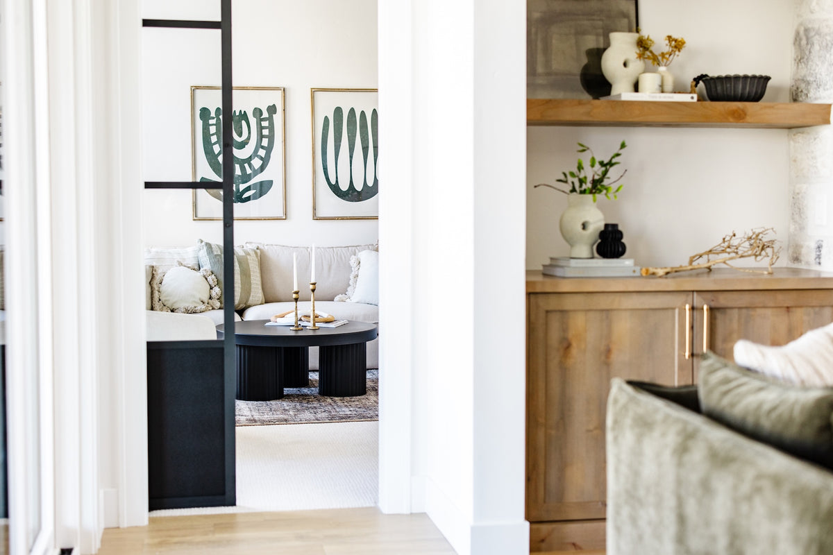 Modern living room with white walls, wooden furniture, and decorative elements.
