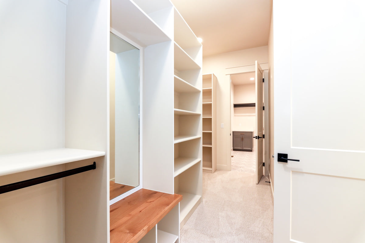 Modern walk-in closet with shelves, mirror, and bench.