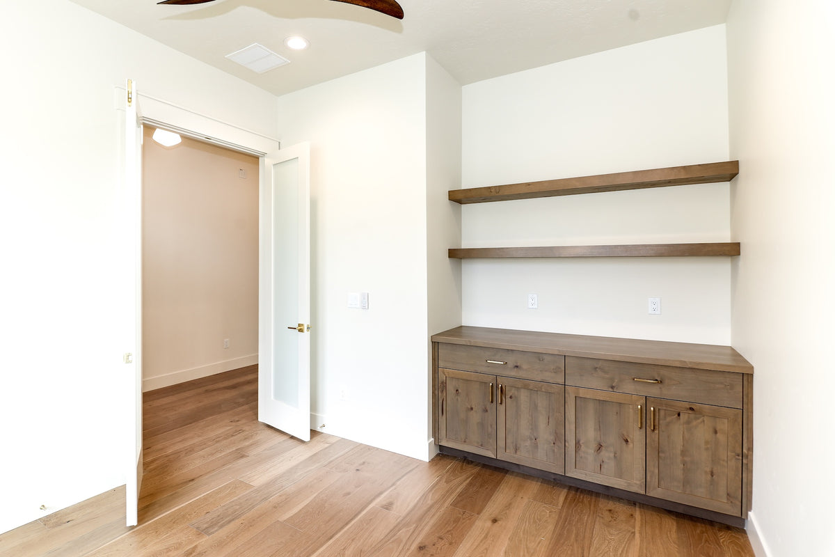 Empty room with wooden flooring, white walls, and a wooden cabinet.