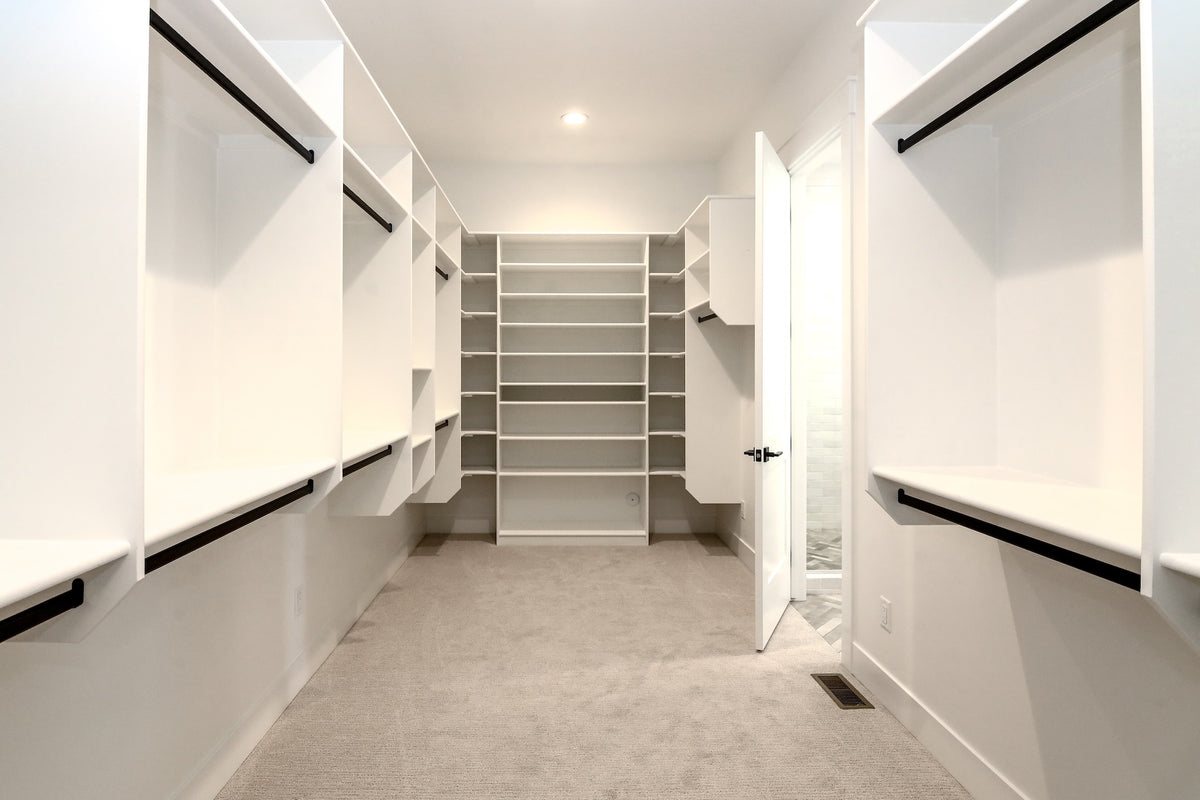 Modern walk-in closet with white shelves and doors.
